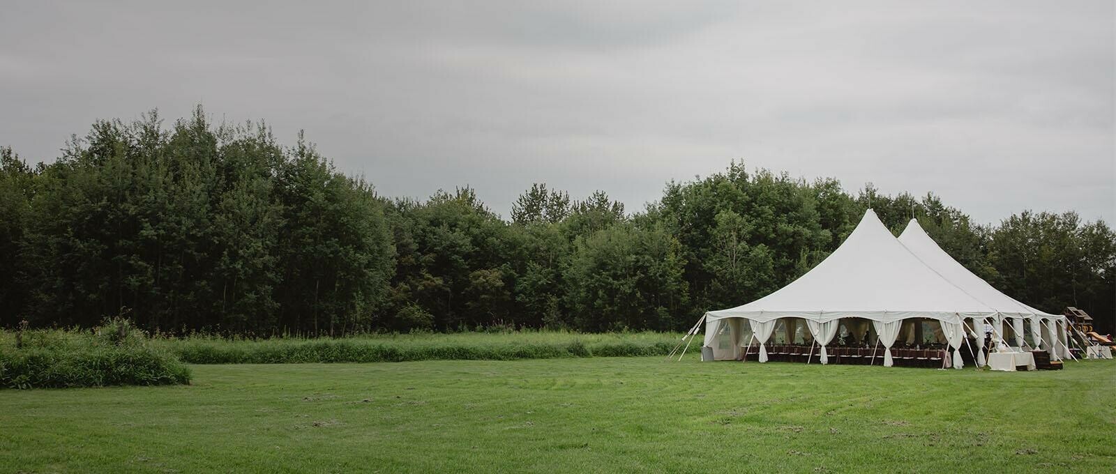 Tent Rentals Regina featuring a white Pole Pent on a grassy field for a wedding reception.